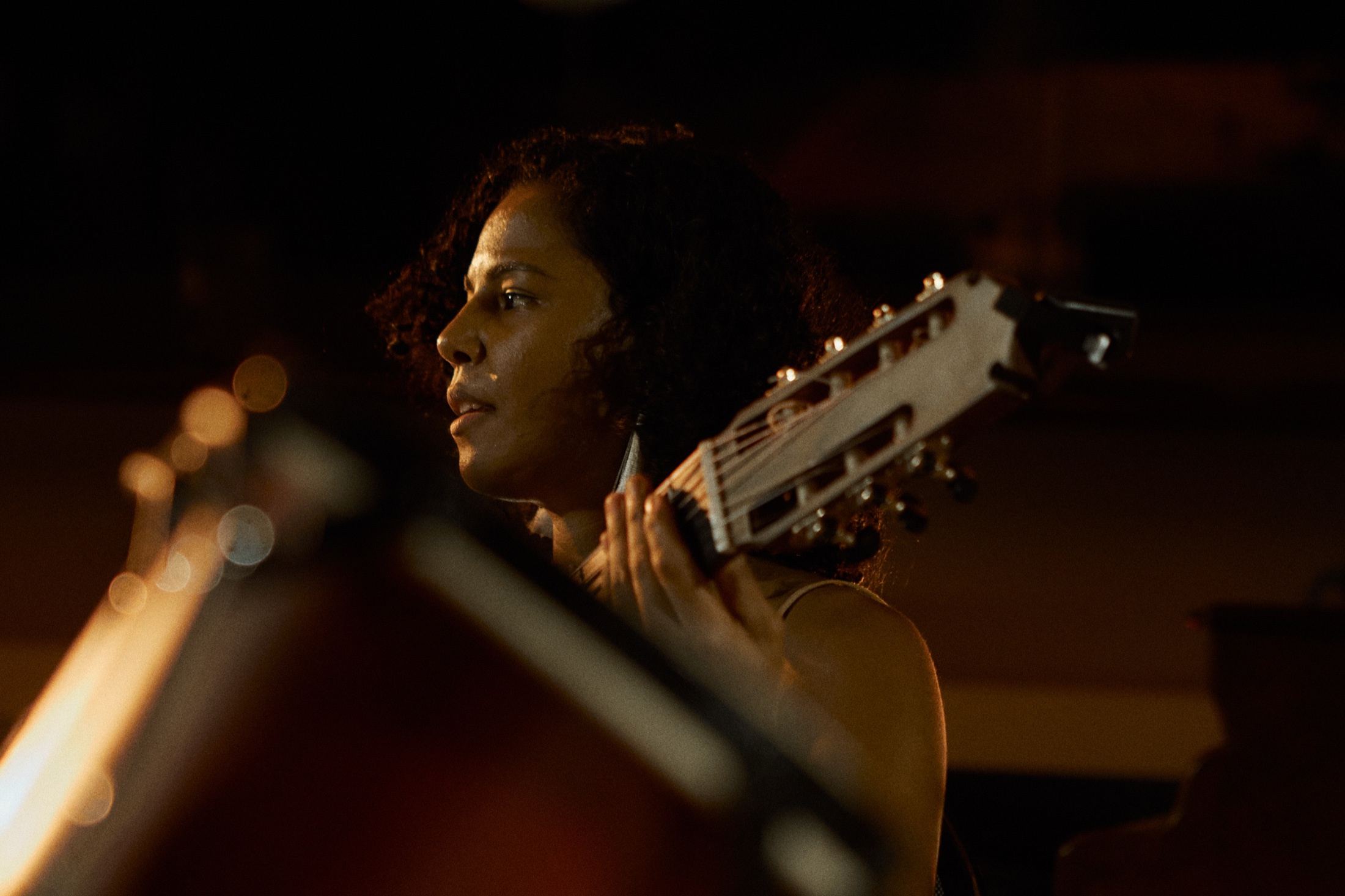 Woman in profile plays guitar in warm low light during an evening performance