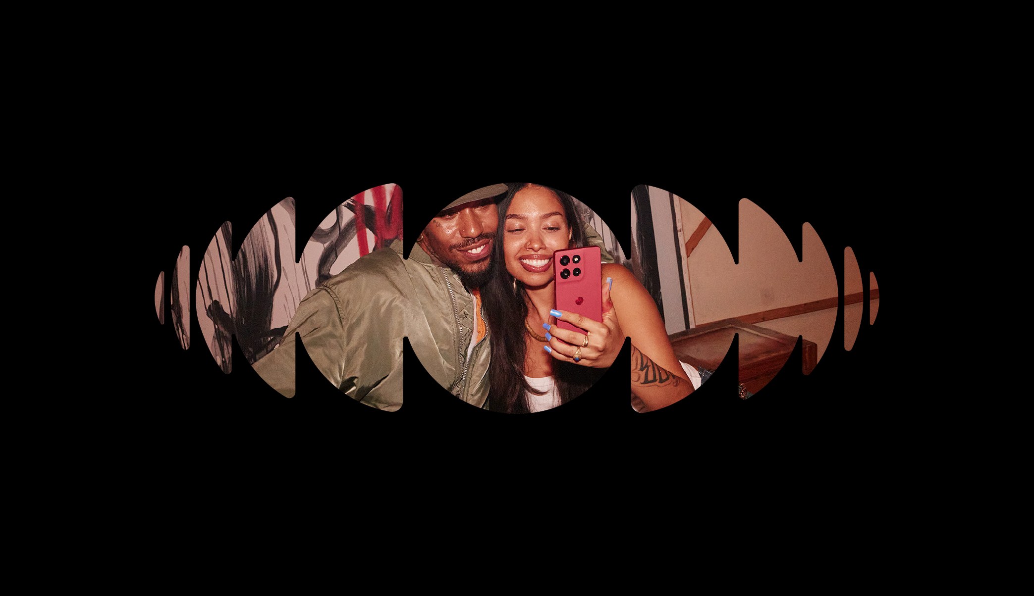 Smiling couple taking a selfie with a pink phone, cropped inside a sound-wave shape on black